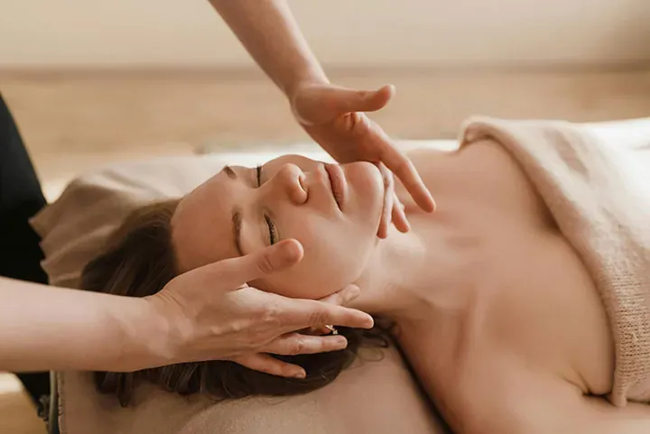Client with eyes closed receiving a relaxing facial infusion, esthetician's hands cradling her jaw